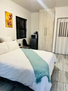 Un dormitorio con una cama blanca con una manta azul. en Zindiza Guesthouse en Witbank