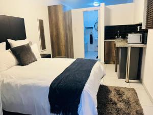 a bedroom with a large bed and a kitchen at Zindiza Guesthouse in eMalahleni
