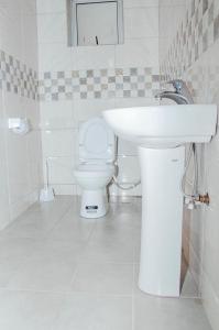 a white bathroom with a sink and a toilet at Hotel Santa Maria in Arua +30 photos