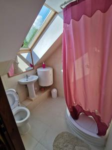 a bathroom with a pink shower curtain and a toilet at Dom na Mazurach Gąsiorowo in Purda