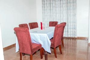 a dining room table with red chairs and a white table cloth at Hotel Santa Maria in Arua