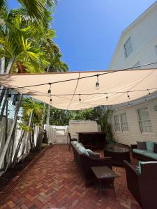 a patio with a tan umbrella and chairs and a table at The Porch on Frances Inn - Adults Exclusive in Key West