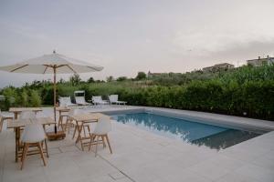 um pátio com mesas, um guarda-sol e uma piscina em Dimora Manfredo Eco B&B Luxury em San Nicola Arcella