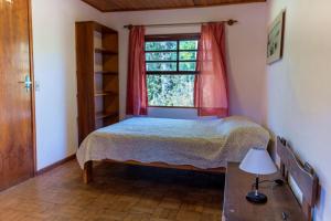 een slaapkamer met een bed en een raam bij Linda Casa de campo c lazer prox Camp do Jordao SP in Campos do Jordão
