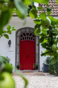 une porte rouge sur un bâtiment blanc avec dans l'établissement La Castagnère de Bergory, à Wervicq-Sud