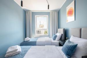 a blue bedroom with two beds and a window at Apartament G312 Łódź Jana Matejki 11 in Łódź