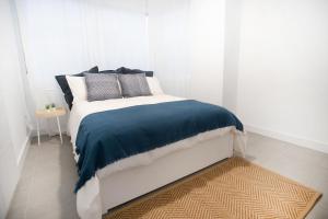 biała sypialnia z łóżkiem z niebieskim kocem w obiekcie Enjoy Malaga on the beachfront w Maladze