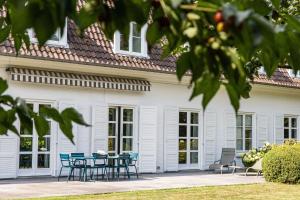 une maison blanche avec des chaises bleues et une table dans l'établissement La Castagnère de Bergory, à Wervicq-Sud