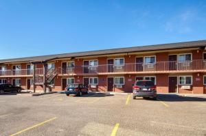 un gran edificio con coches estacionados en un estacionamiento en Motel 6-Lethbridge, AB, en Lethbridge