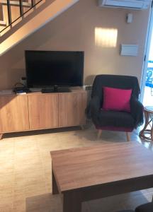 ein Wohnzimmer mit einem TV und einem Stuhl mit einem rosa Kissen in der Unterkunft Vera Natura Las Olas in Vera