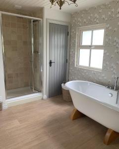 a bathroom with a tub and a shower and a window at Sage Gables Mourne Mountains in Annalong
