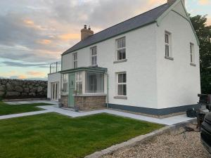 a white house with a green door in a yard at Sage Gables Mourne Mountains in Annalong