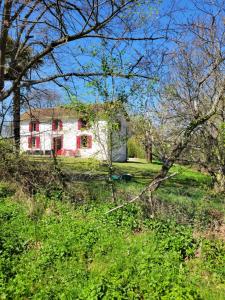 a white house with red windows in a field at Petite maison dans les bois 