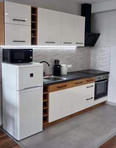 La cuisine est équipée de placards blancs et d'un réfrigérateur blanc. dans l'établissement Lively Debrecen, à Debrecen