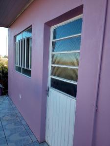 uma casa cor-de-rosa com uma porta branca e uma janela em Apartamento com churrasqueira, ótima localização. em Cachoeira do Sul