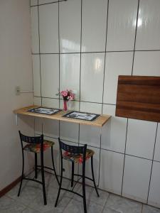 a counter with two chairs and a table with flowers at Apartamento com churrasqueira, ótima localização. in Cachoeira do Sul