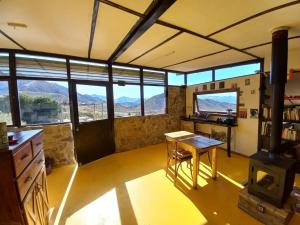a room with a table and a stove and windows at La Ramada - refugio in Potrerillos
