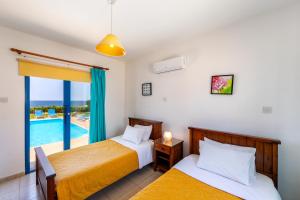 een slaapkamer met 2 bedden en een zwembad bij Diana Seaside Villas in Pomos