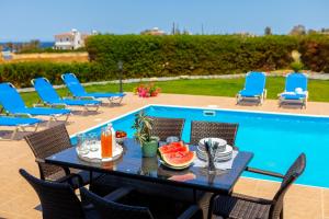 een tafel met fruit erop naast een zwembad bij Diana Seaside Villas in Pomos
