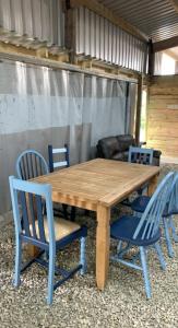 a wooden table with blue chairs in a shed at Bell tent 3 Glyncoch isaf farm in Llwyn-Dafydd
