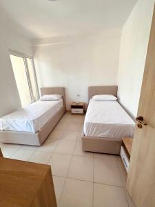 a bedroom with two beds and a window at Pine Breeze Apartment Gjiri i Lalezit in Draç