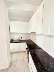 a kitchen with white cabinets and a black counter top at Pine Breeze Apartment Gjiri i Lalezit in Draç