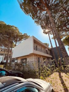 a house with a car parked in front of it at Pine Breeze Apartment Gjiri i Lalezit in Draç