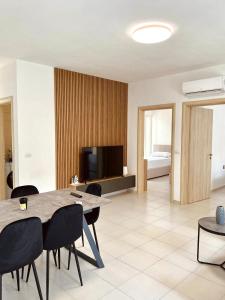 a living room with a table and chairs and a television at Pine Breeze Apartment Gjiri i Lalezit in Draç
