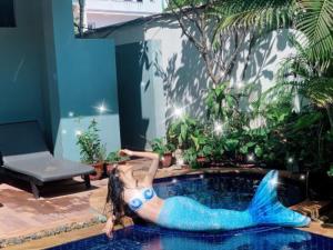 a woman in a blue dress laying in a pool at Bayon Boutique Hotel សណ្ឋាគារប៊ូទិកបាយ័ន in Siem Reap
