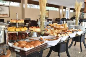 a table filled with different types of bread and pastries at Barreirinhas Flat Gran Solare 210 in Barreirinhas