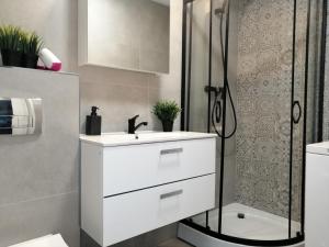 biała łazienka z umywalką i prysznicem w obiekcie MARINA Brzeźno Apartment przy plaży w Gdańsku