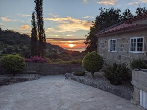 a house with a sunset in the background at A Casa do Río Bueu in Bueu