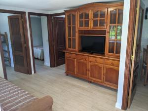 a living room with a tv in a wooden cabinet at A Casa do Río Bueu in Bueu