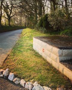 a stone retaining wall next to a road at Bell tent 1 Glyncoch isaf farm in Llwyn-Dafydd