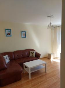 a living room with a brown couch and a white coffee table at Mieszkanie przy Kanale Łuczańskim in Giżycko