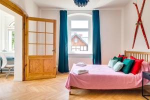 - une chambre avec un lit rose et des oreillers colorés dans l'établissement QQłka Apartament z widokiem, à Szklarska Poręba