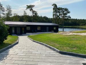 ein Gehweg, der zu einem Gebäude neben einem See führt in der Unterkunft Gråbogården event and conference center in Gråbo