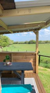 a picnic table on a deck with a view of a field at Yurt glyncoch isaf farm in Llangrannog