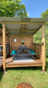 a wooden gazebo with a picnic table and benches at Yurt glyncoch isaf farm in Llangrannog