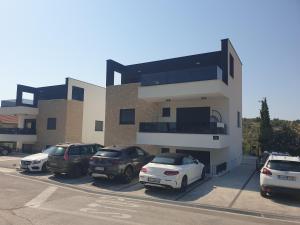 een gebouw met auto's geparkeerd op een parkeerplaats bij Apartman Retro with heated pool and gym for 8 in Murter