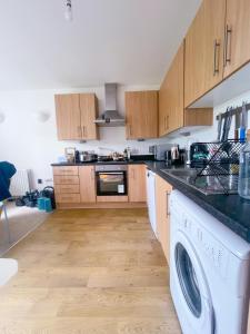 a kitchen with wooden cabinets and a washer and dryer at Cosy 1-bedroom apartment in Greater London in London