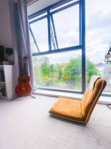 a chair in front of a window with a guitar at Cosy 1-bedroom apartment in Greater London in London