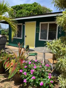 a green and yellow house with a table and flowers at The Cottage at Ohia Kai. TVNCU#1354 in Kapaa