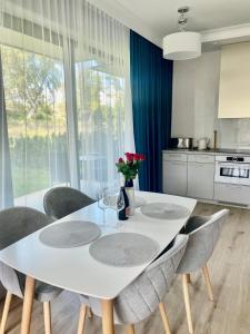 a white dining room table with chairs and a kitchen at Rezydencja Niechorze 108 Prestige in Niechorze