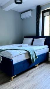 a blue bed in a bedroom with a window at Aparthotel w Dolinie Stawów Zator by Housine in Las