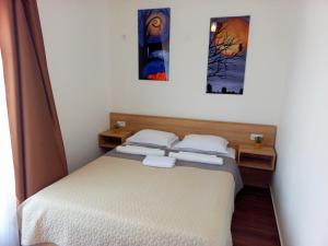 a bedroom with a bed and two paintings on the wall at Iraida-4 in Dobra Voda