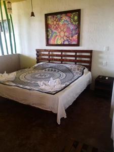 uma cama num quarto com uma pintura na parede em Namasté Zipolite Suites em Zipolite