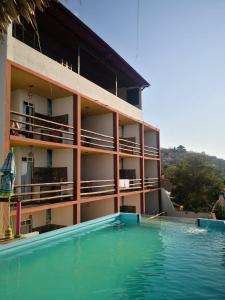 a hotel with a swimming pool in front of a building at Namasté Zipolite Suites in Zipolite