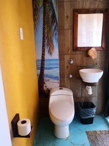 a bathroom with a toilet and a sink and palm trees at Namasté Zipolite Suites in Zipolite