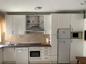 eine Küche mit weißen Schränken und einem weißen Kühlschrank in der Unterkunft Arenalita in S’Arenal